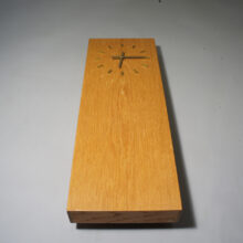Wall clock in oak with details in brass.