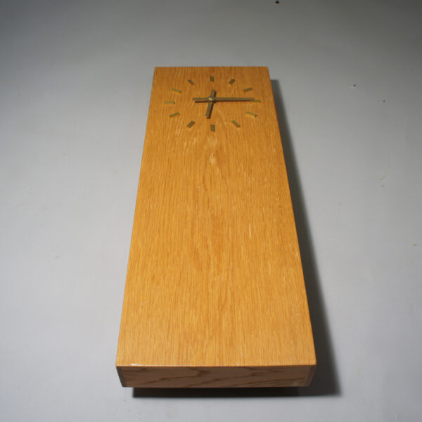 Wall clock in oak with details in brass.